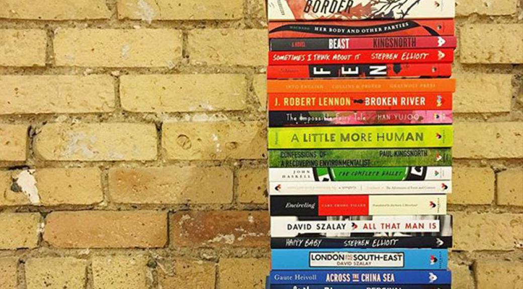 stack of published paperback books beside a brick wall