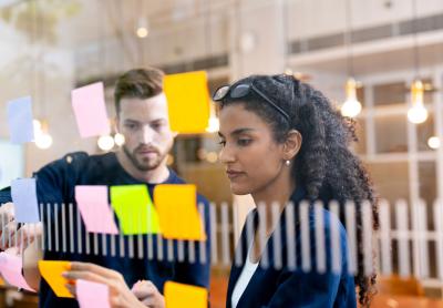 Business Professionals Organizing Sticky Notes Together During Agile Project Management and Collaborative Planning Session