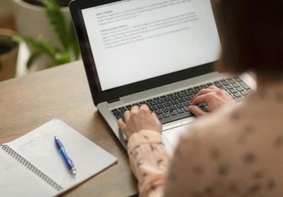 woman reviewing content on a screen with notepad nearby