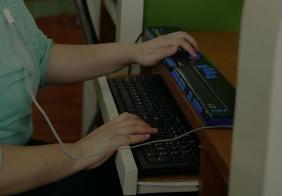 Asian woman with blindness disability using computer with braille in workplace