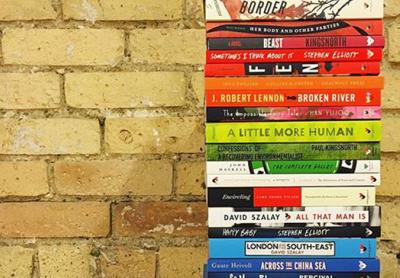 stack of published paperback books beside a brick wall