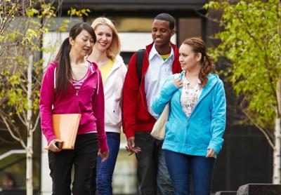 four college students walking together on campus, talking to each other