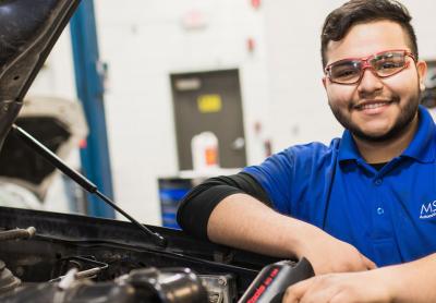 Automotive repair student in a garage with vehicle