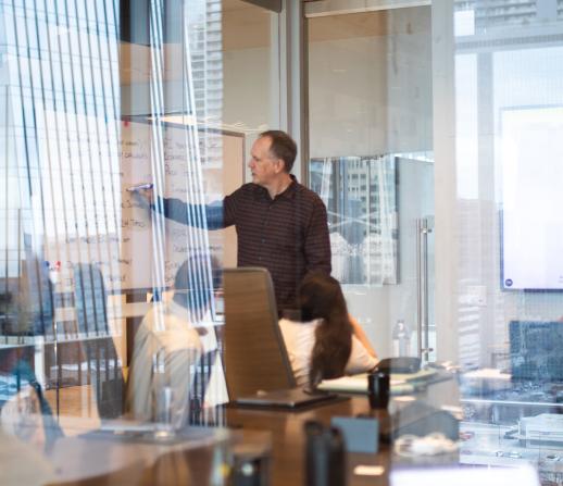 adult man presenting to a group of coworkers in a conference room