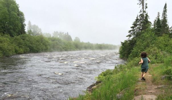 youth running alongside a running river in Minnesota