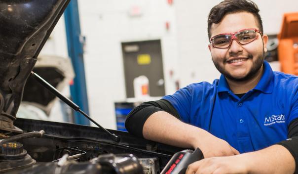 Automotive repair student in a garage with vehicle