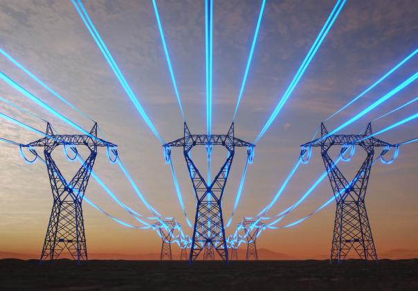 utility towers in a field at sunset with the wires highlighted in bright blue