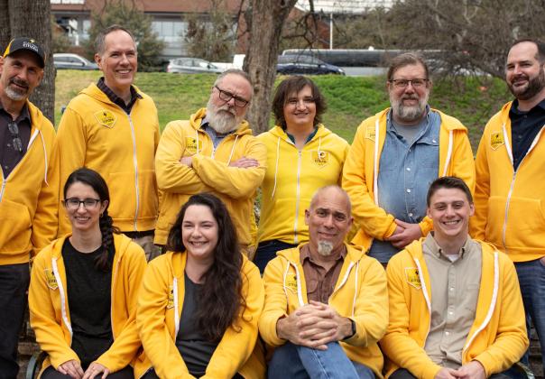 members of the Electric Citizen team, gathered together outdoors, all wearing gold colored hoodies
