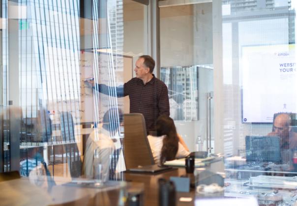 adult man presenting to a group of coworkers in a conference room