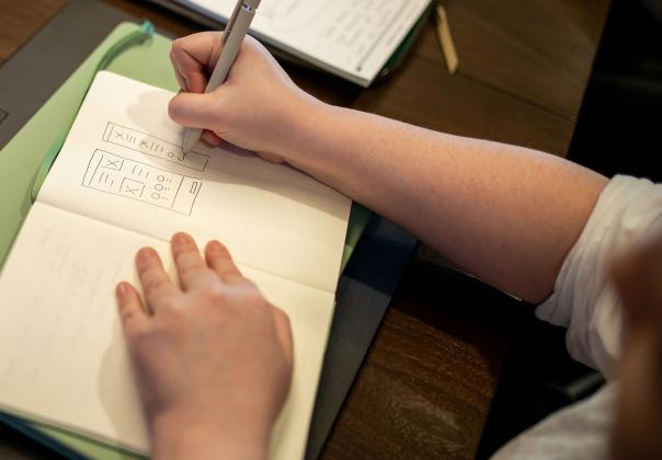 sketching out a wireframe on paper with a pen