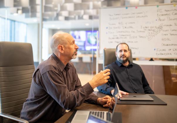 two adults talking about work at a conference table