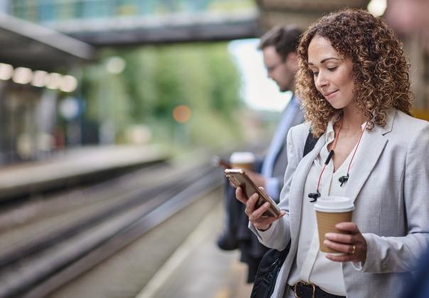 woman reading on her phone and waiting for a train