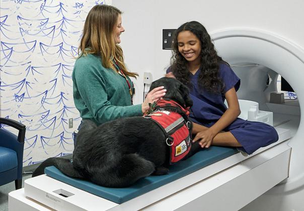 woman getting health care CAT scan with support dog along