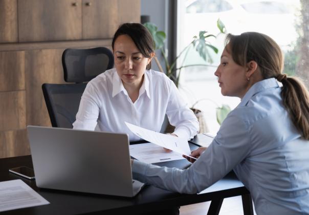 two adult professionals discussing work in an office setting