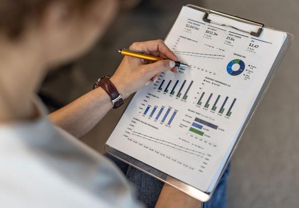 Woman reviewing a printed page with various analytics and graphs