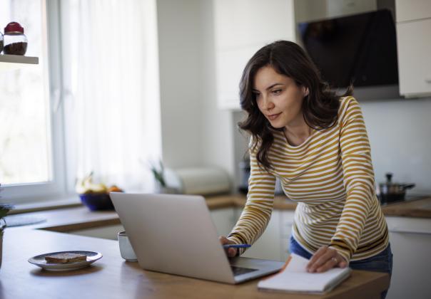 A woman looks over a laptop in excitement.