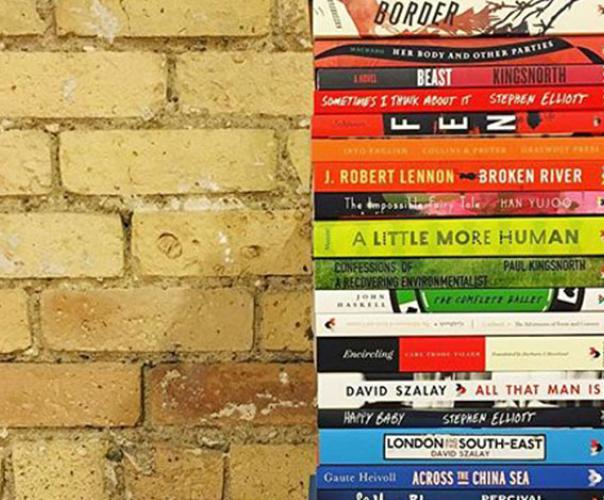 stack of published paperback books beside a brick wall