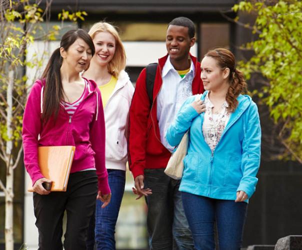 four college students walking together on campus, talking to each other