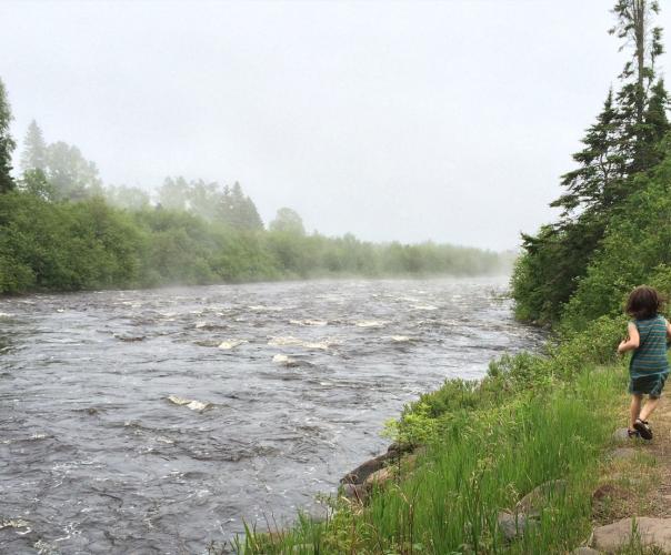 youth running alongside a running river in Minnesota