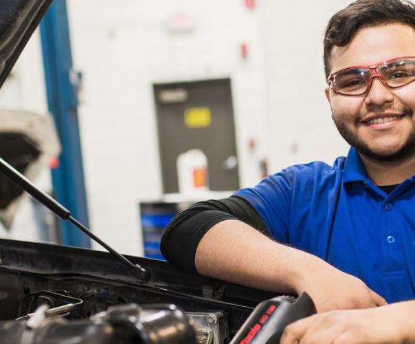 Automotive repair student in a garage with vehicle