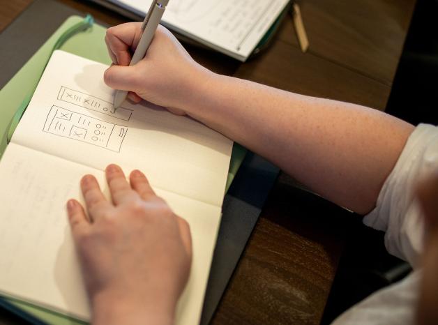 close up of a person sketching a wireframe in a notebook