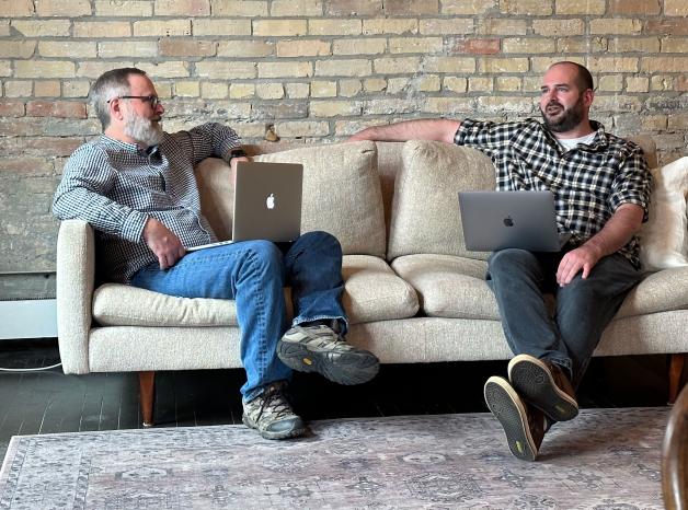 two adult team members conversing on a couch