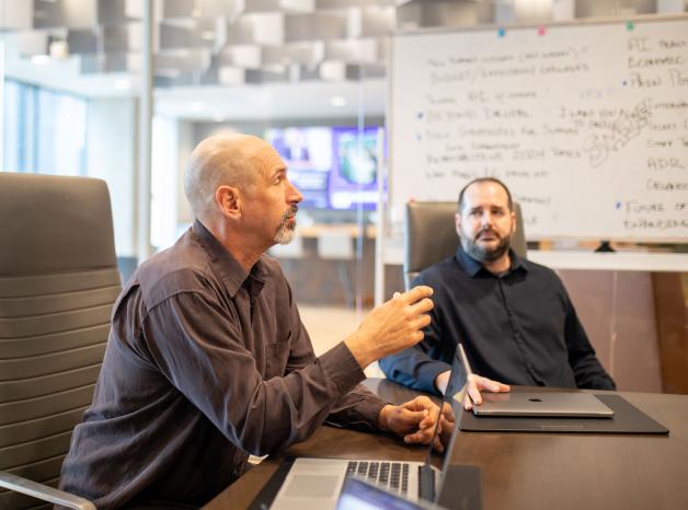 two adults talking about work at a conference table