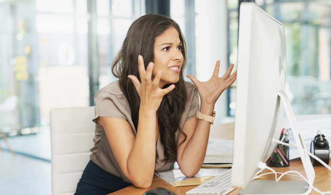 business professional frustrated with her website, looking at a screen and raising hands in frustration