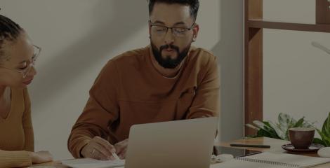 two adults working together at a desk with an open laptop