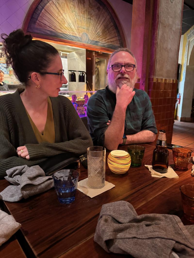 two team members at dinner together, talking over drinks