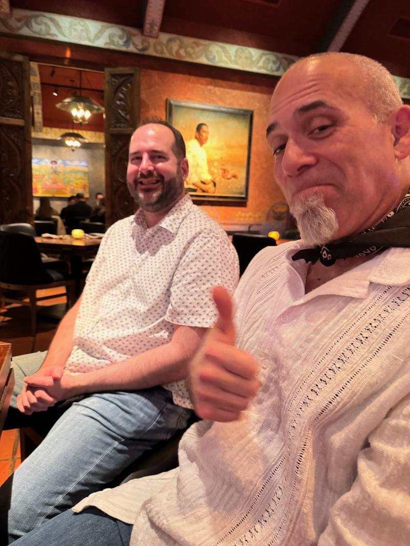 two adult males seated next to each other in a restaurant