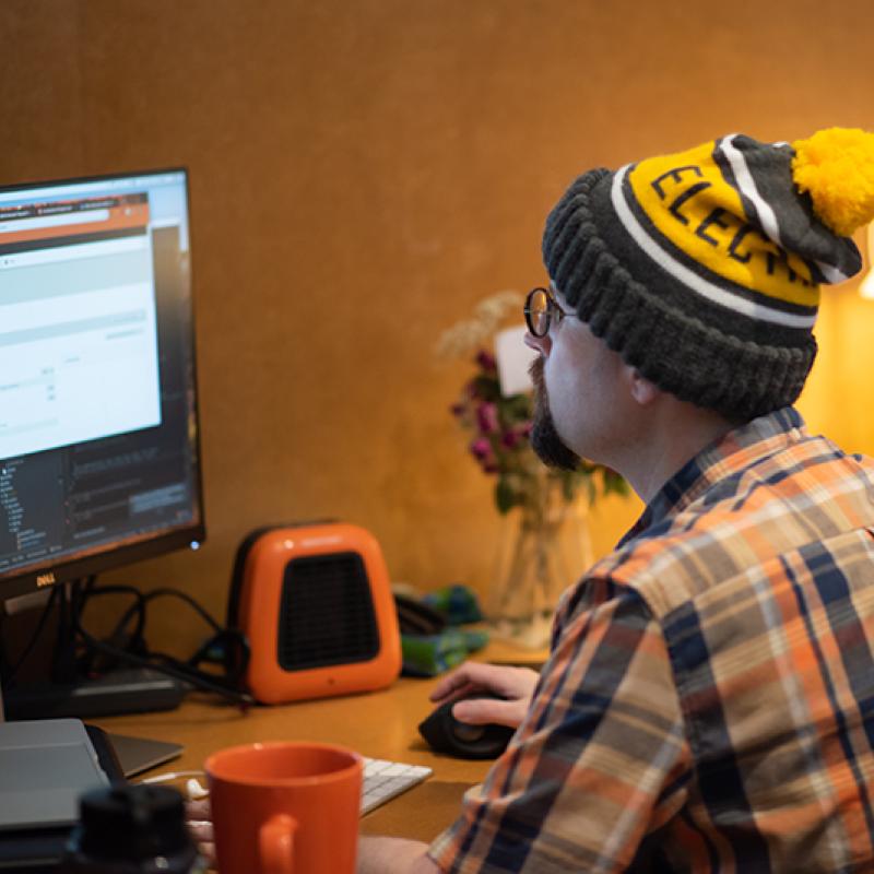 web developer sitting at desk coding on computer