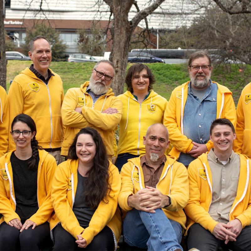 member of Electric Citizen's team, standing outdoors wearing matching gold hoodies