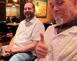 two adult males seated next to each other in a restaurant