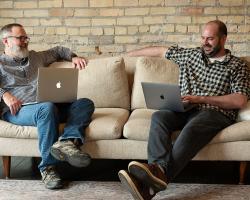 Briand and Adam on the couch together with laptops