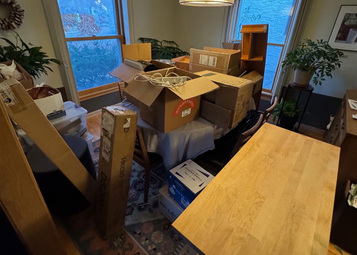 various boxes and office items scattered around a dining room table