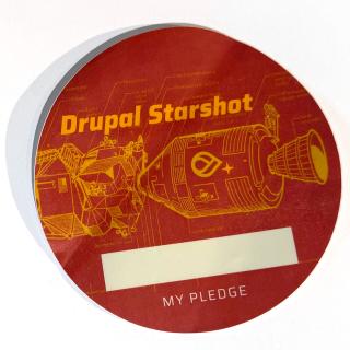 Dark red Drupal Starshot sticker with yellow type and outline of spacecraft