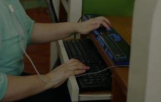 Asian woman with blindness disability using computer with braille in workplace