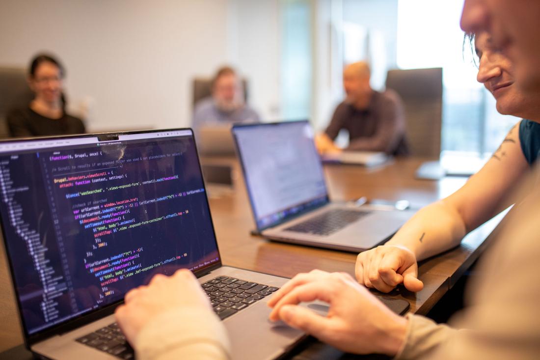 two developers reviewing code on a laptop