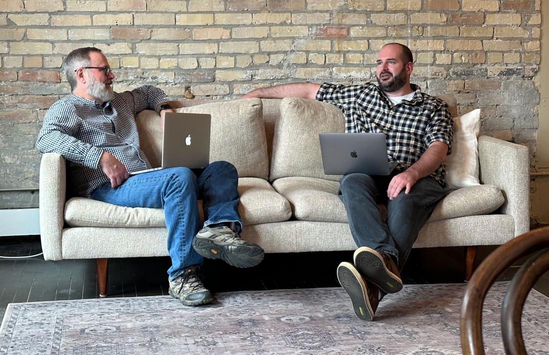 two adult team members conversing on a couch