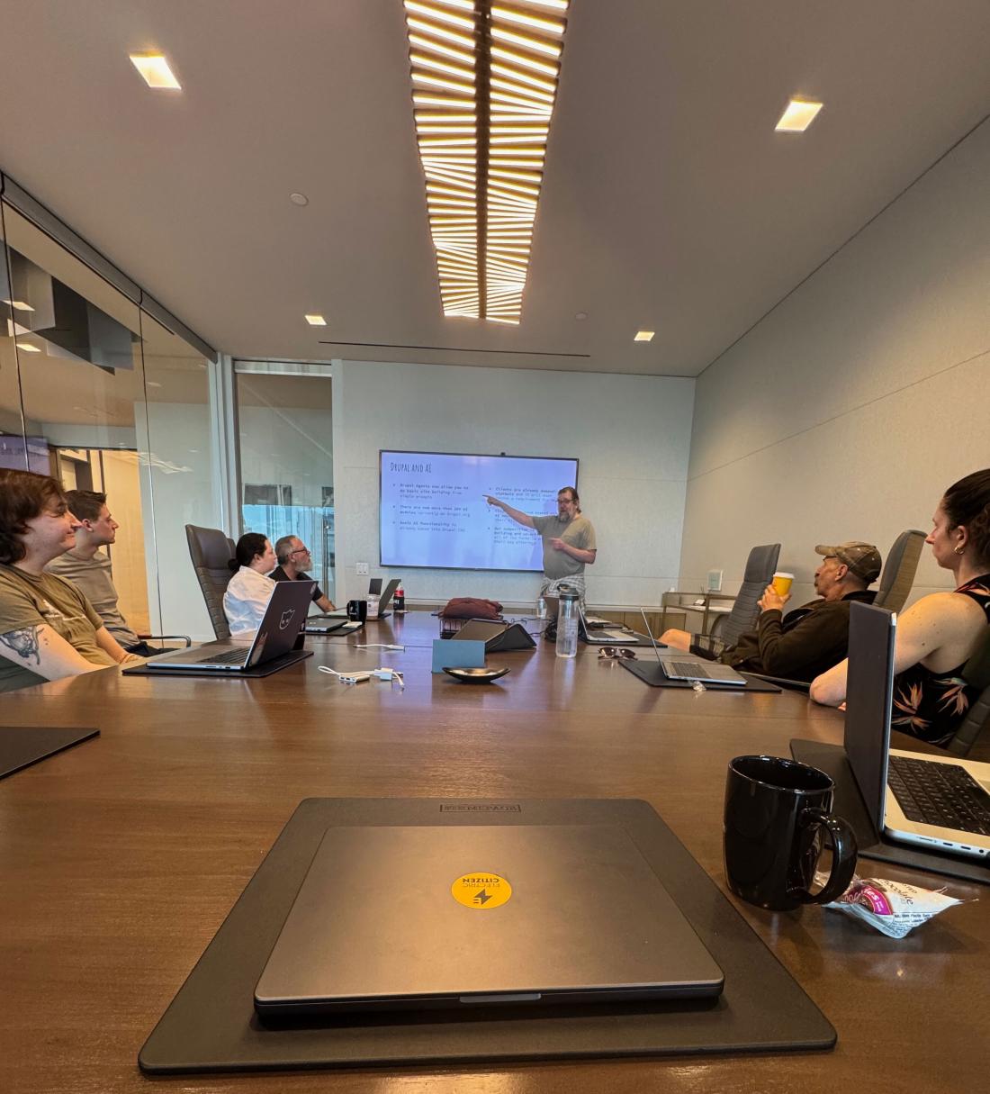 adult male presenting slides in a conference room